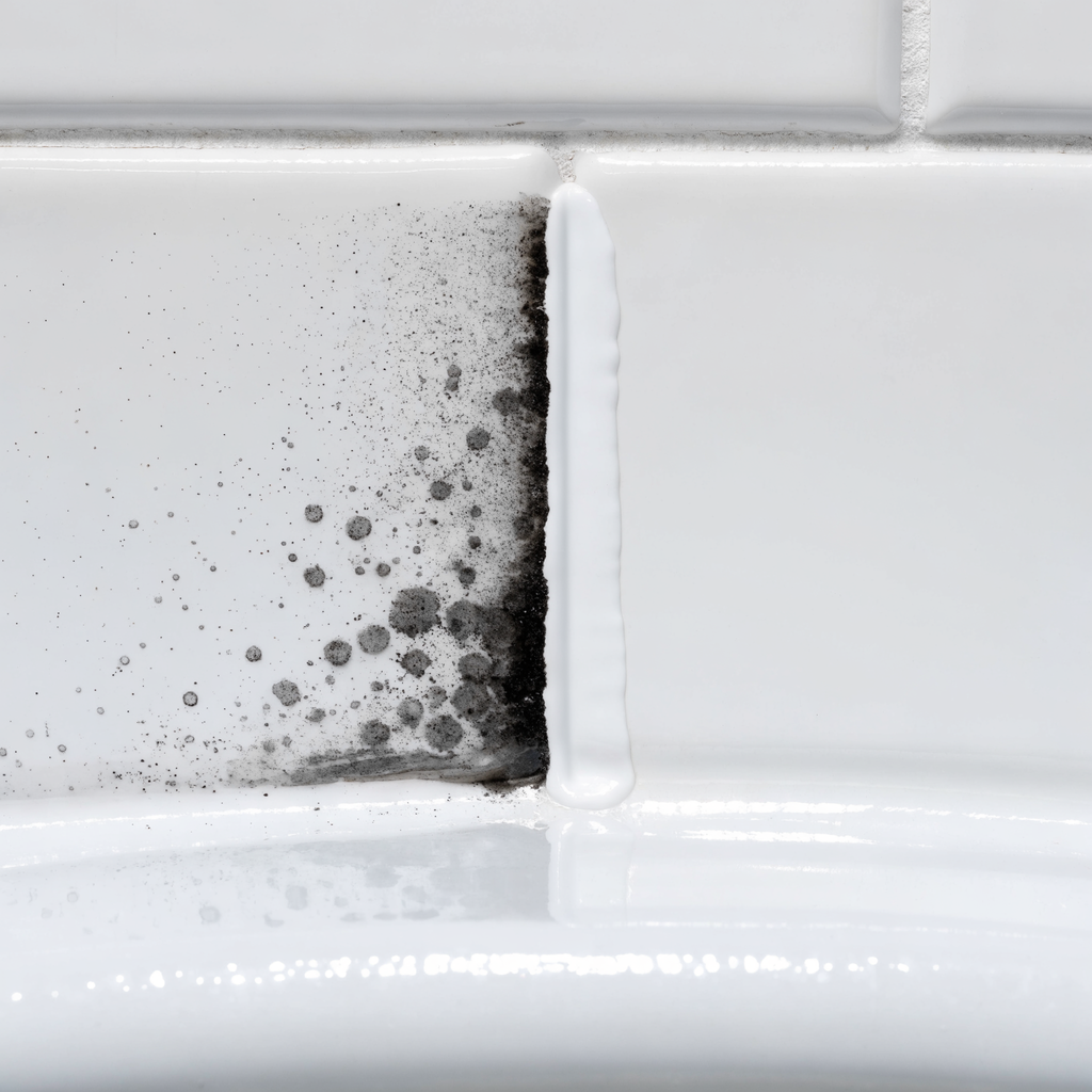 Bathroom caulk seam shown half stained dark and half clean white