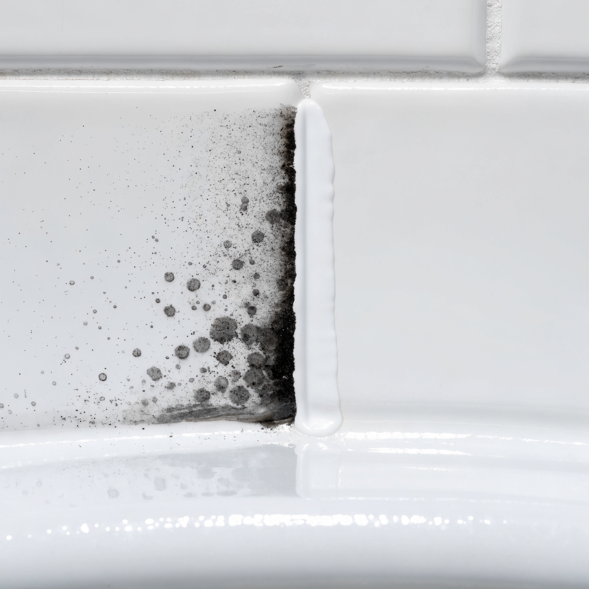 Bathroom caulk seam shown half stained dark and half clean white