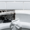 Bathroom caulk seam half stained black and half wiped clean white